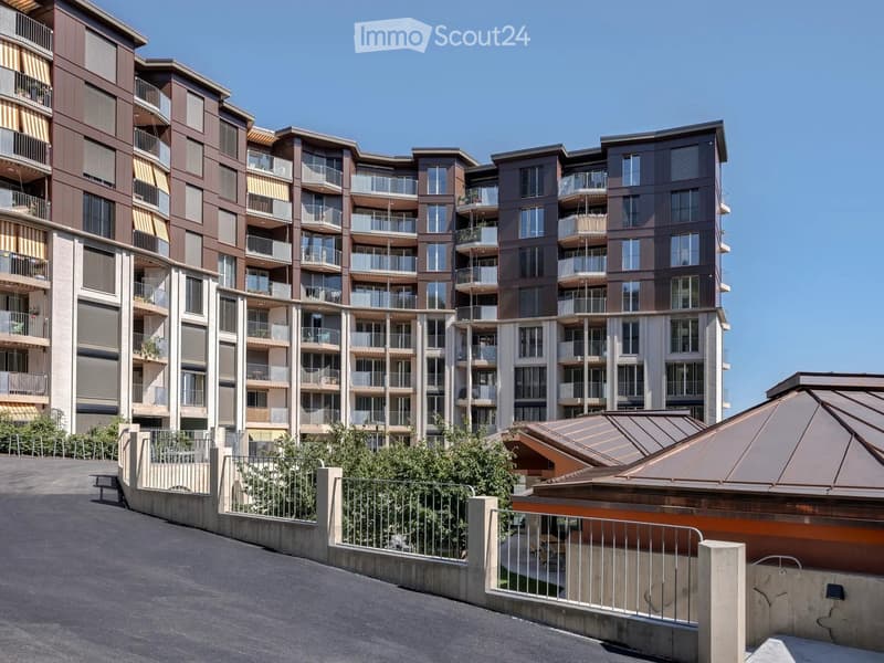 Modern multi-story residential building with balconies, large windows, and contemporary design.