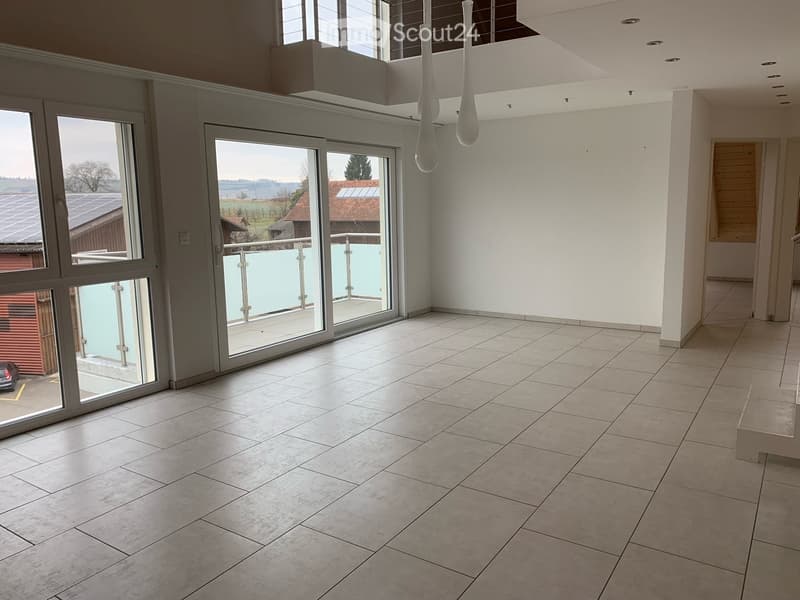 Empty room with tiled floor, large windows, and a balcony area visible through glass doors.