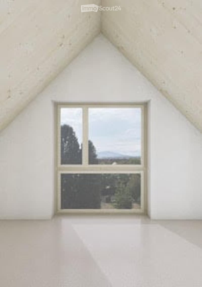 Empty attic room with slanted white walls, large window offering a scenic view of trees and mountains.
