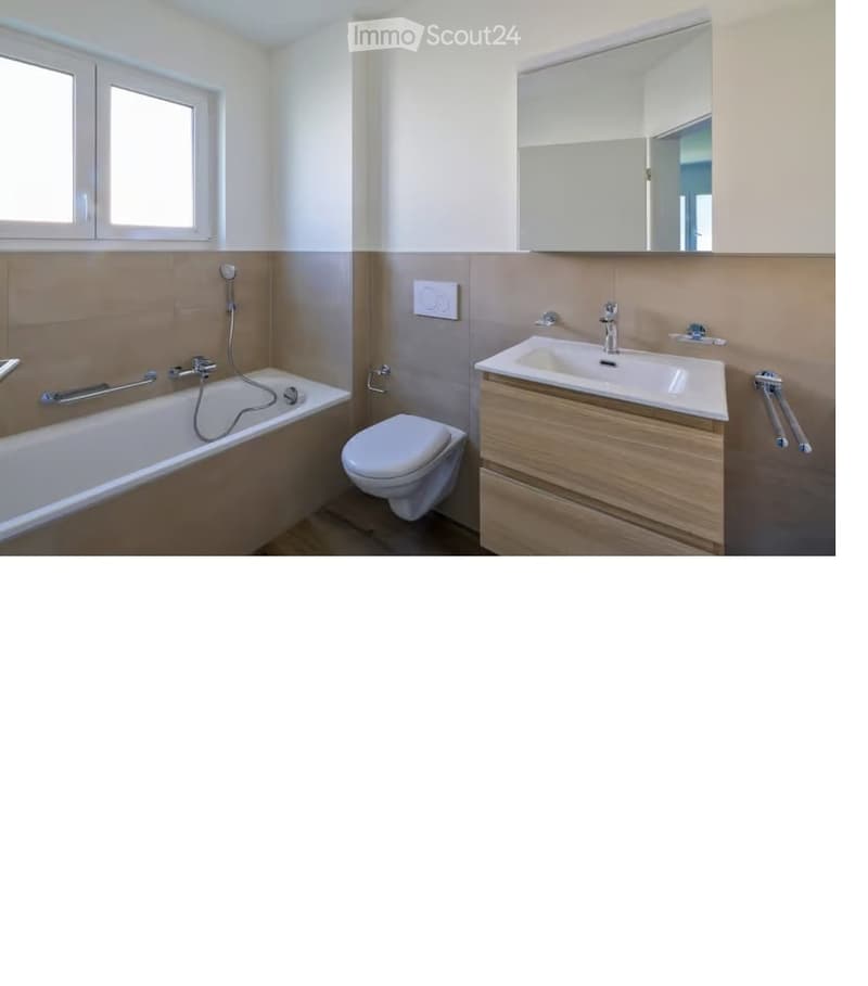 Modern bathroom with a bathtub, toilet, sink, and mirror. Features a wooden vanity with a double sink and a large mirror above it. The walls are painted in a light neutral color with a beige accent on the lower half.