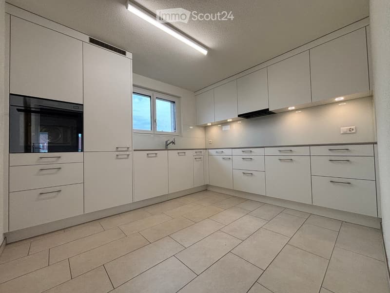 Modern kitchen with white cabinets, tiled floor, and a window above the sink.