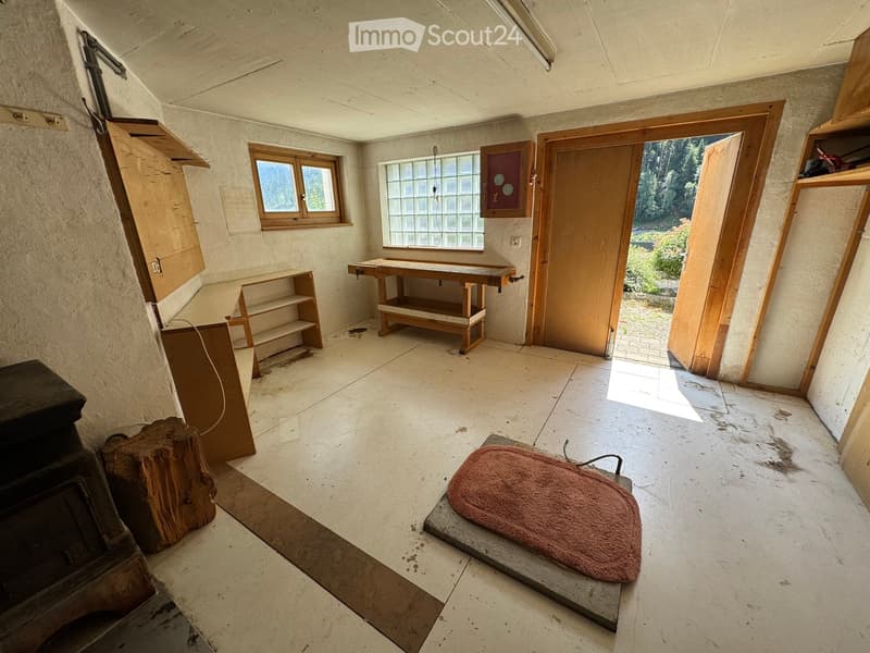 Empty room with concrete floor, wooden door, windows, and a small wooden table. No furniture or equipment present.