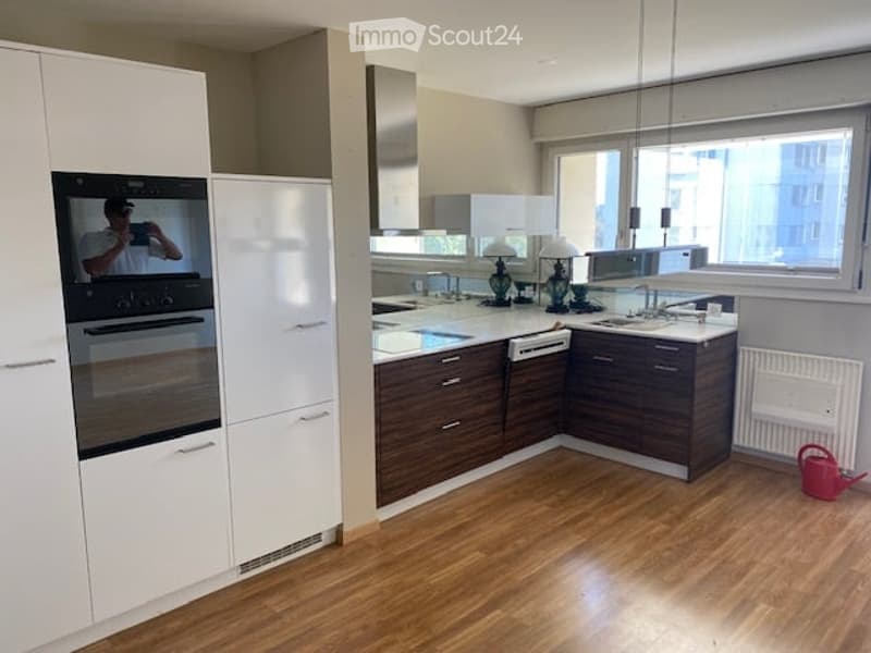 Modern kitchen with white and dark wood cabinets, stainless steel appliances, a central island with a sink, and a table lamp on the counter.