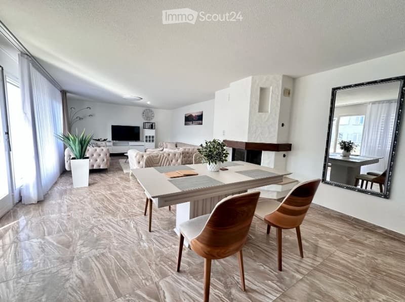 Modern living room with a large window, marble flooring, a sofa, coffee table, dining table with chairs, and a fireplace area.