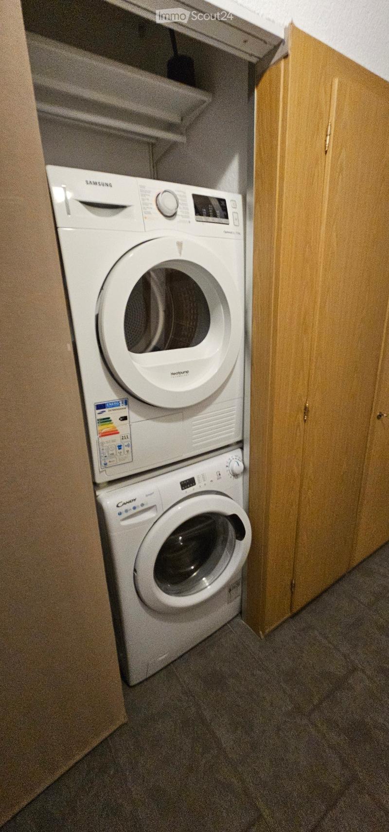 Compact bathroom with a stacked washing machine and dishwasher unit, wooden cabinets, and tiled floor.