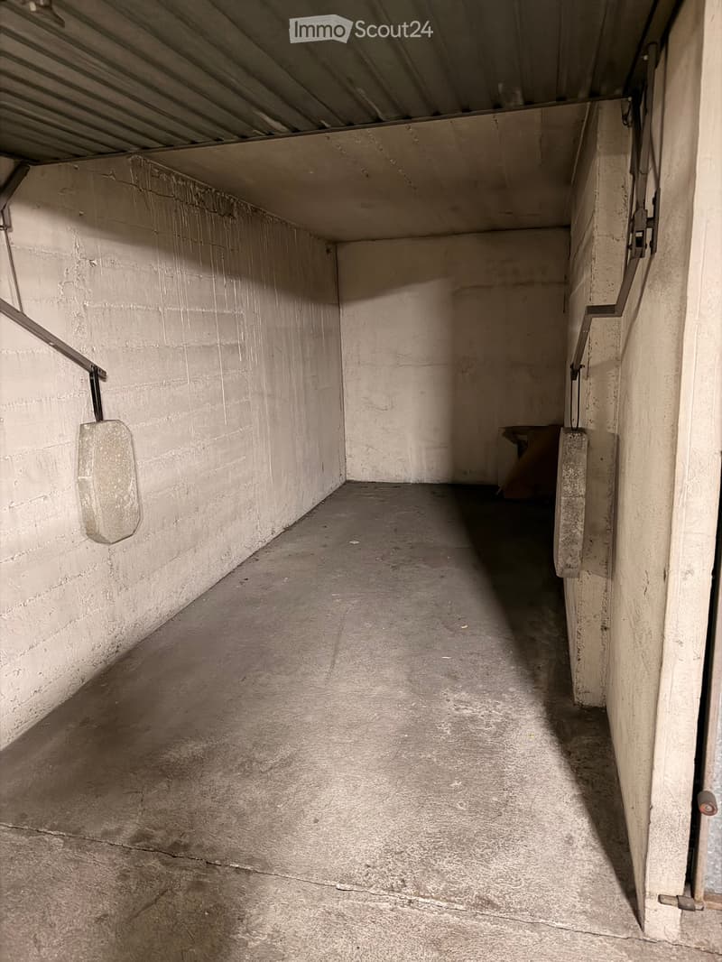 Empty concrete corridor with metal railings on both sides, leading to a doorway at the end.