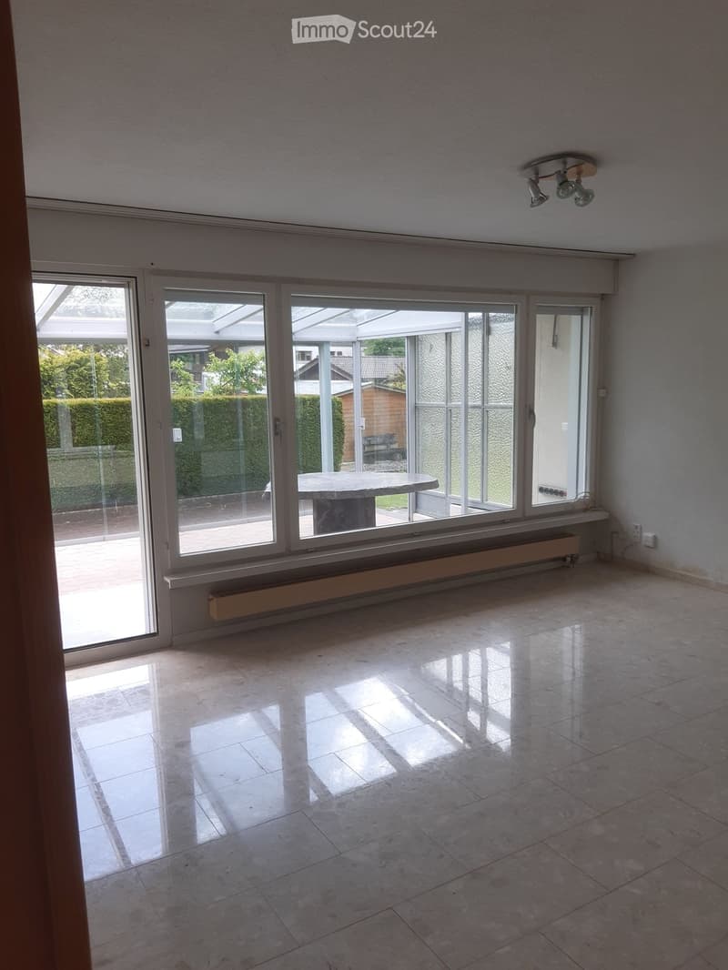 Empty room with large glass sliding doors leading to an outdoor area, tiled floor, and visible radiator under the windows.