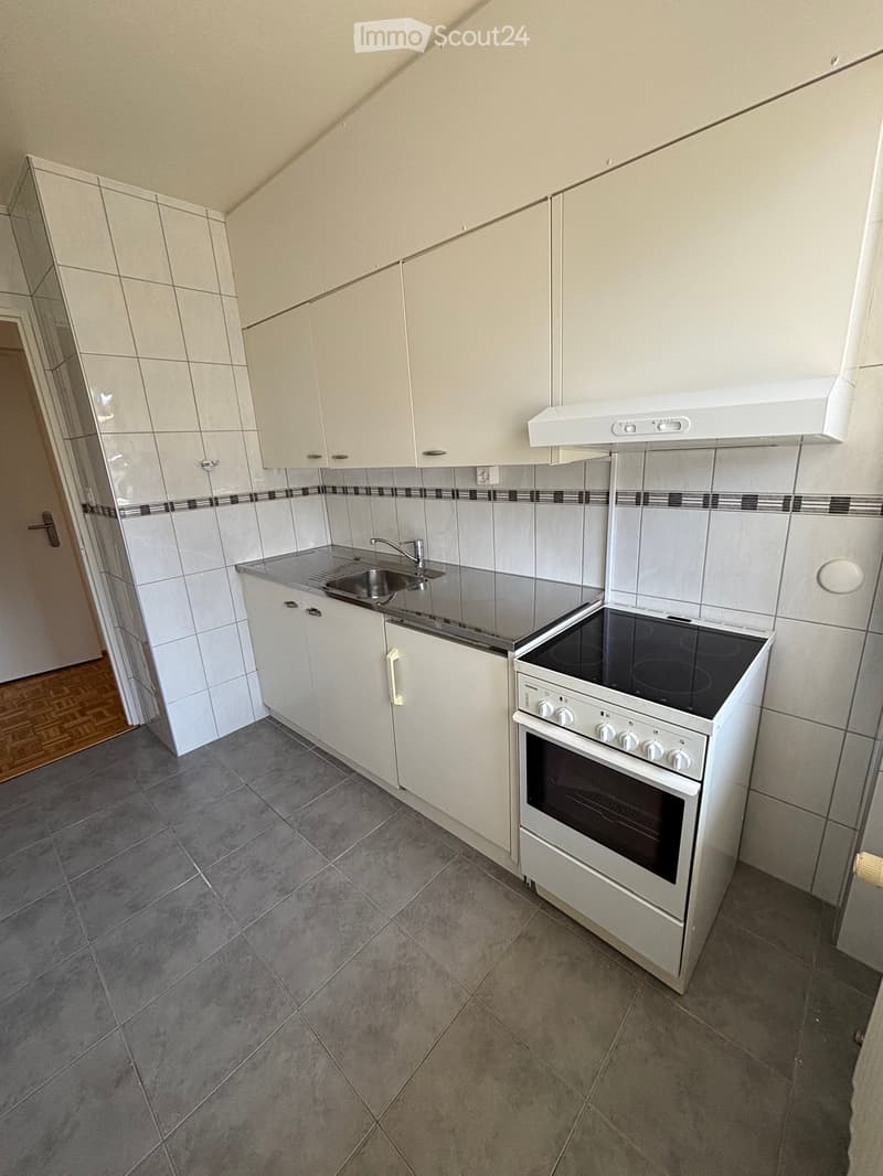 Modern kitchen with white cabinets, stainless steel sink, electric oven, and tiled backsplash.
