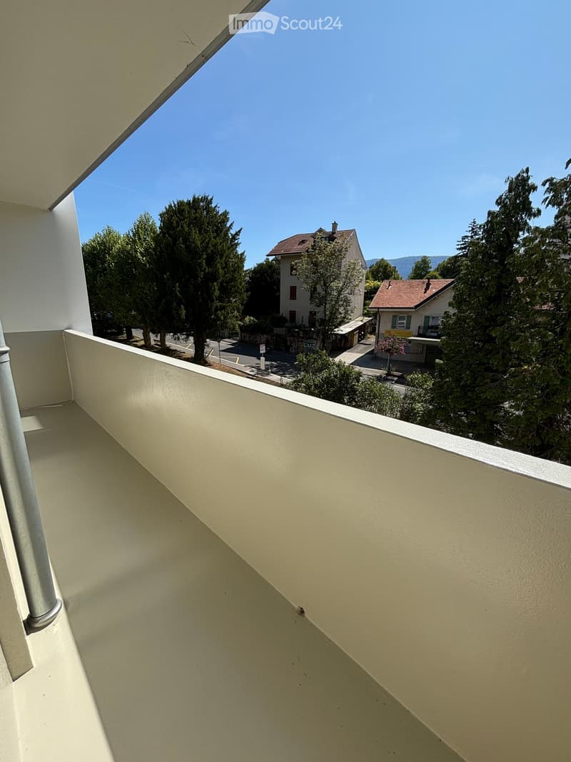 Balcony with a view of a residential area, trees, and houses under a clear blue sky.