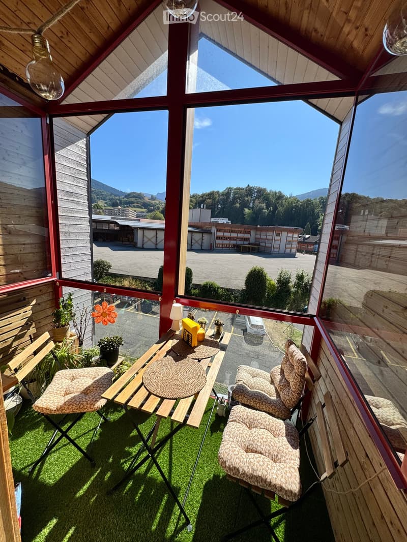 Balcony with wooden furniture, green artificial grass, and scenic mountain view.