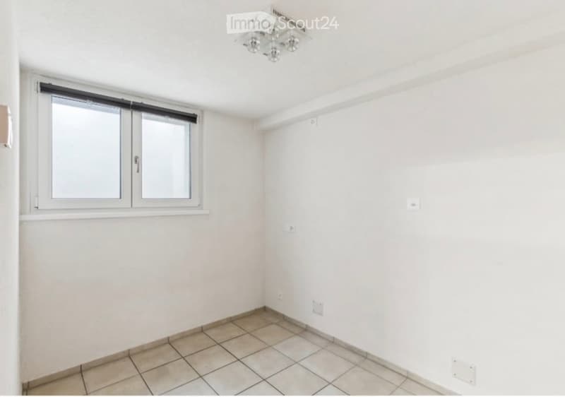 Empty room with white walls, tiled floor, and a window with blinds. No furniture or equipment present.