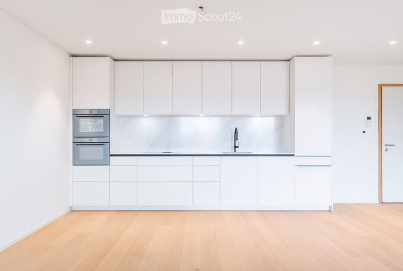 Modern kitchen with white cabinets, stainless steel oven, and a sleek sink with a modern faucet.