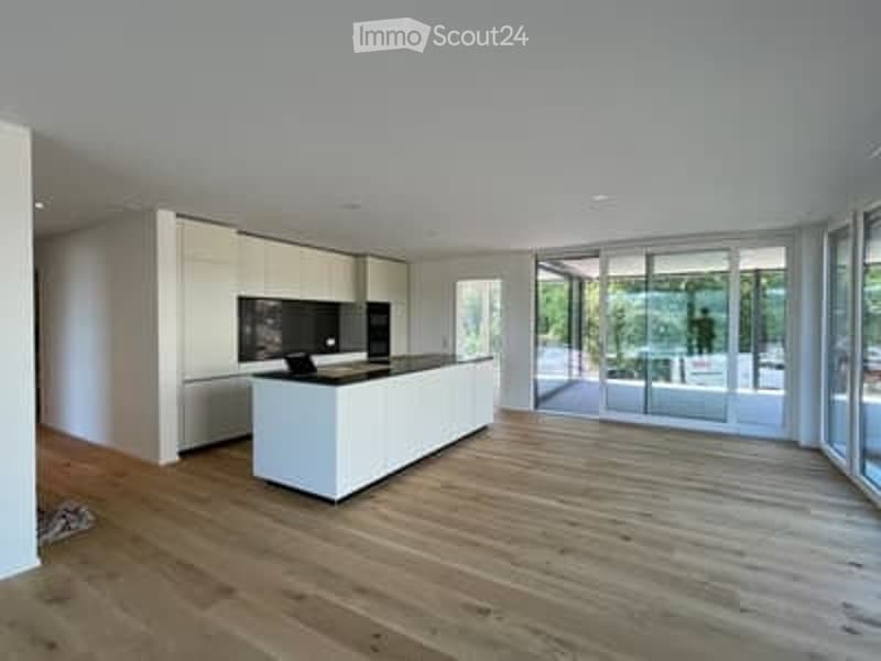 Modern, minimalist kitchen with white cabinetry, a central island, and large glass doors leading to a view.