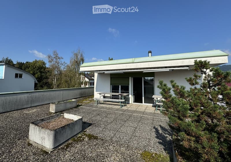 white house, green roof, outdoor seating area, gravel ground, trees