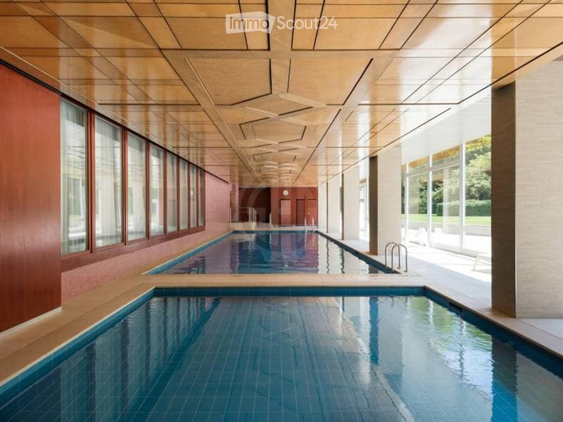 Indoor swimming pool area with two pools, large windows, and a modern ceiling design.