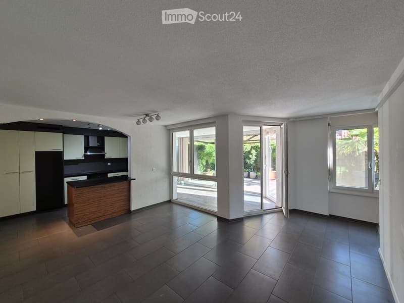 Modern kitchen with white cabinets, dark countertop, and large windows leading to a patio.