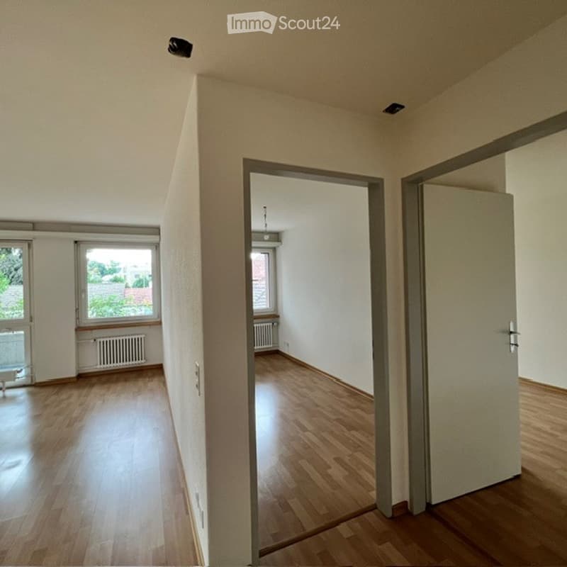 Empty room with wooden flooring, white walls, and large windows. No furniture or equipment present.