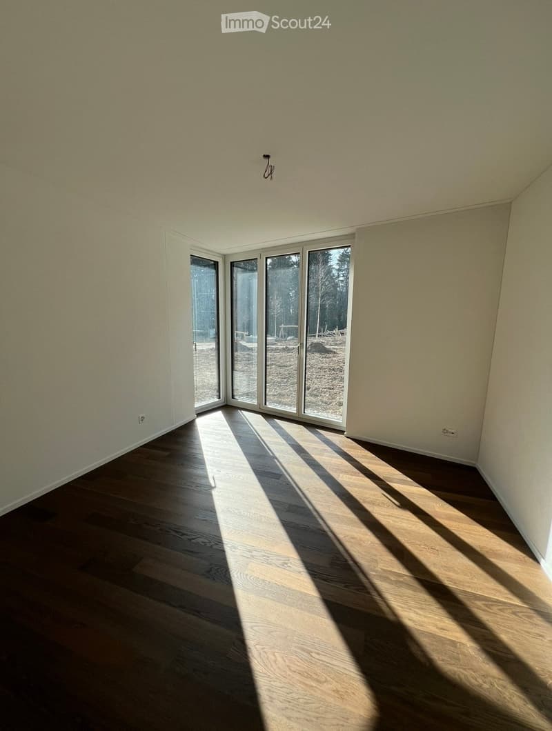 Empty room with wooden flooring and large sliding glass doors leading to an outdoor area.