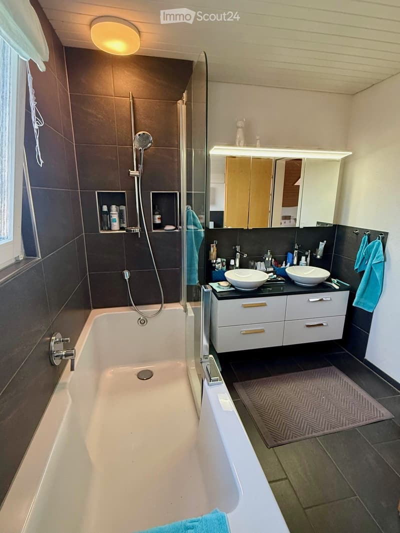 Bathroom with bathtub, double sink, mirror, and shower