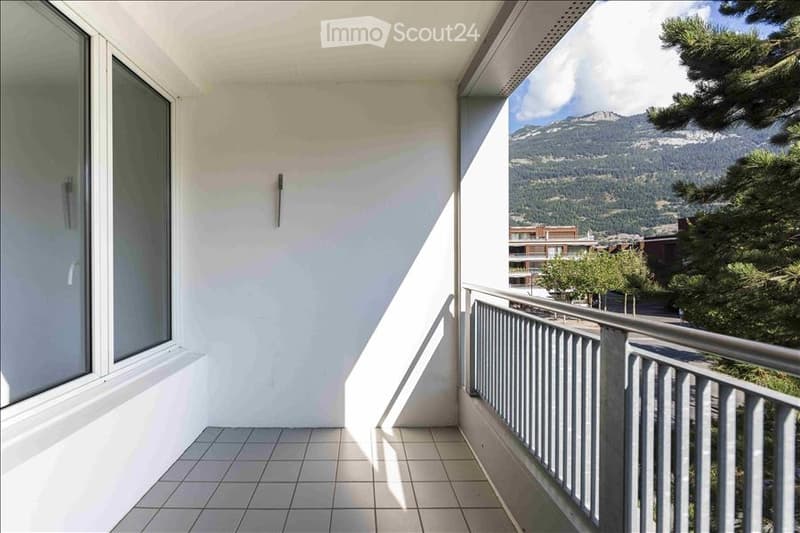 Balcony with tiled floor, white walls, large windows, and a scenic mountain view.