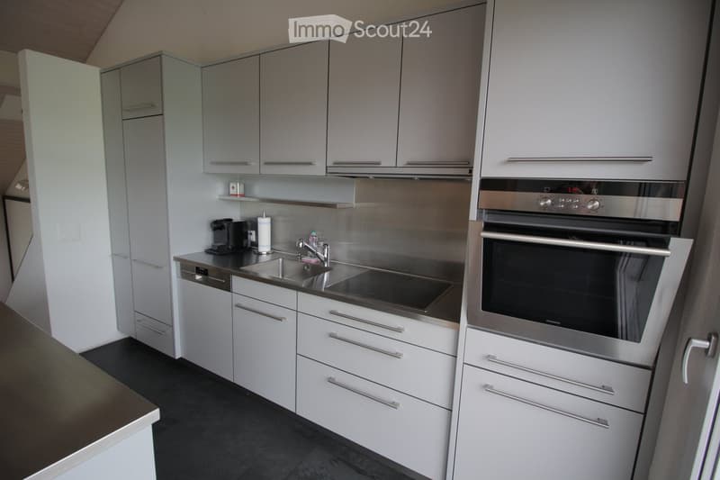 Modern kitchen with white cabinets, stainless steel appliances, and a black countertop.