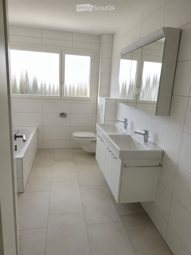 Modern bathroom with white tiles, a bathtub, toilet, double sink, and a large mirror above the sink.