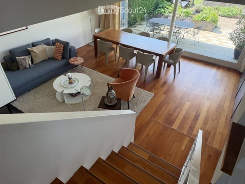 {"visible_features": ["Garden / Outdoor Area"], "type": "Furnished Room", "objects": ["sofa", "coffee table", "dining table", "chairs", "stool", "vase", "floor lamp"], "description": "Open-plan living and dining area with wooden flooring, a grey sofa, a c