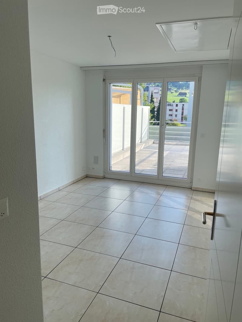 Empty room with tiled floor, white walls, and large sliding glass doors leading to a balcony.