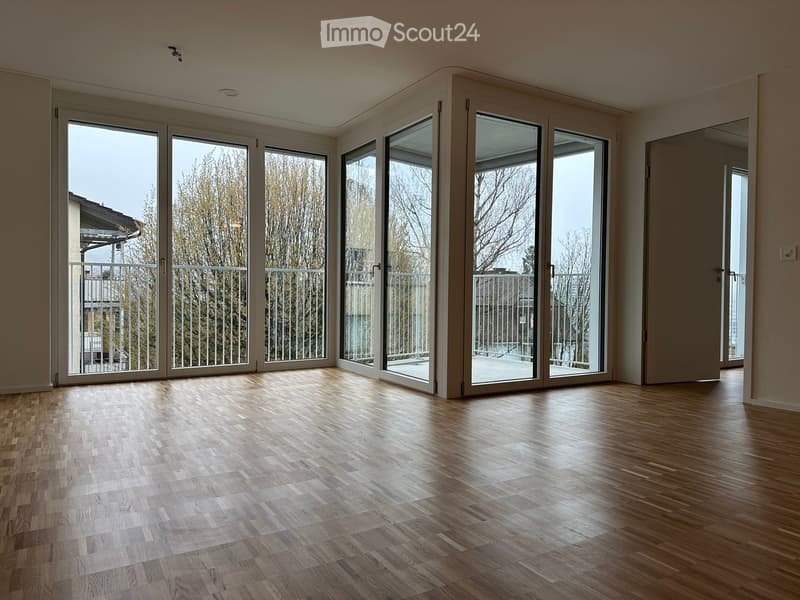 Empty room with wooden flooring and large sliding glass doors leading to a balcony.