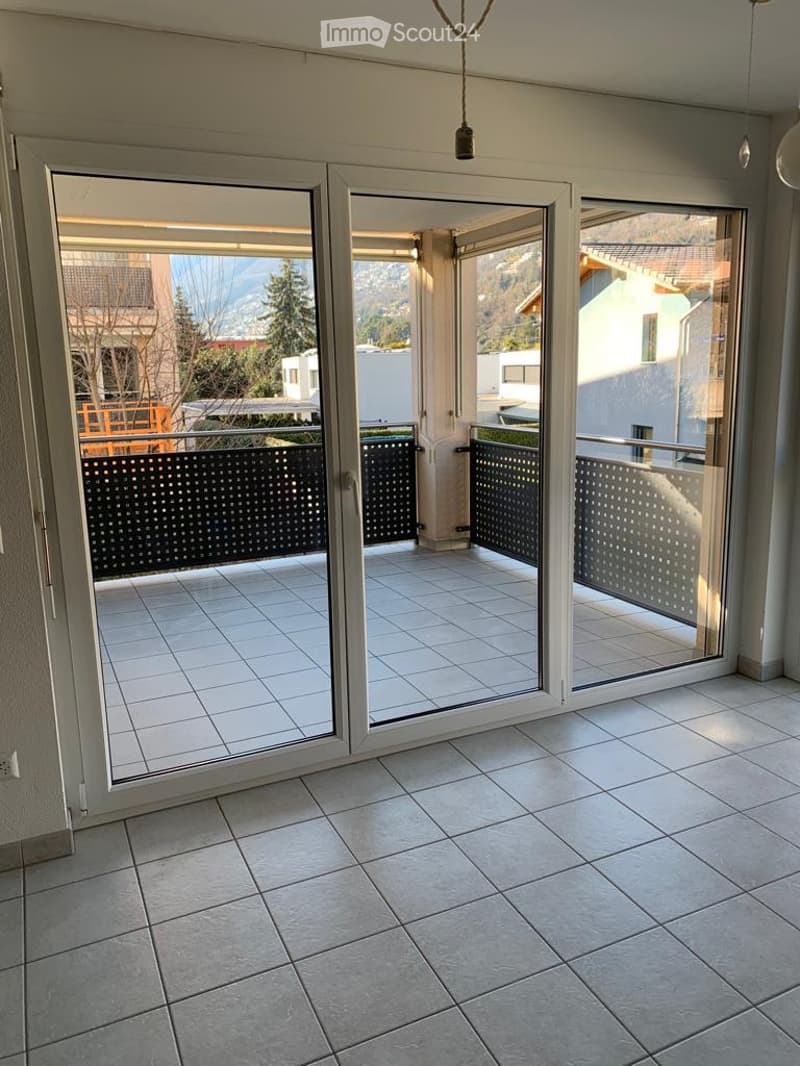 Spacious balcony with tiled flooring, large glass sliding doors, and a scenic mountain view.