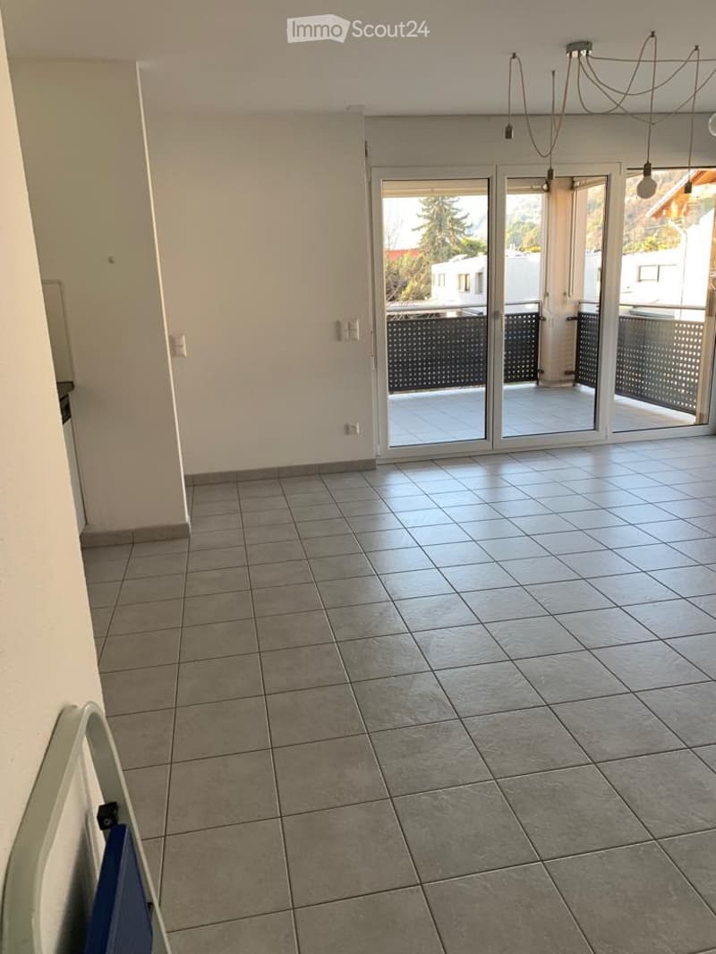 Empty room with tiled floor, white walls, and large sliding glass doors leading to a balcony or terrace area.