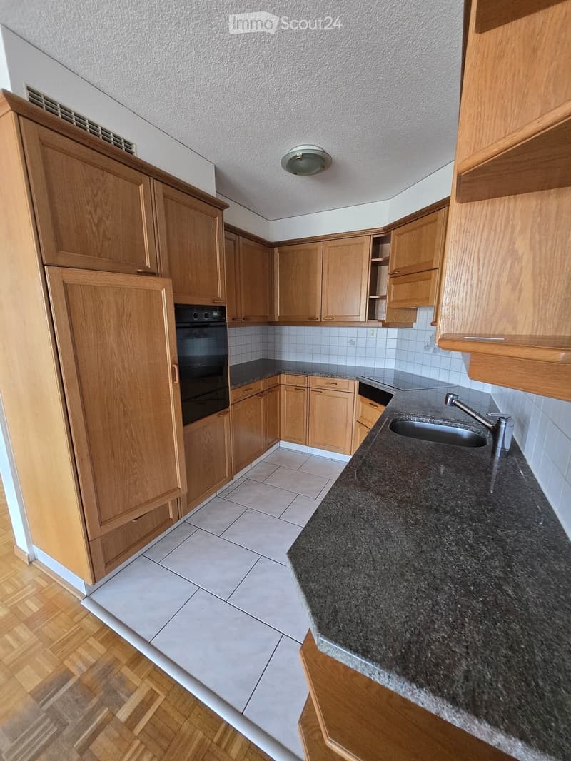 Modern kitchen with wooden cabinets, granite countertop, sink, and built-in oven.