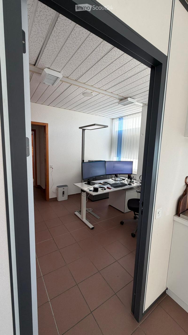 modern office, white walls, brown tiled floor, desk with computer monitors, office chair, shelves on the wall