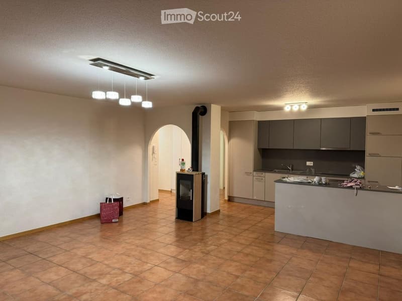 Open-plan living and kitchen area with tiled flooring, modern kitchen cabinets, a fireplace, and pendant lighting.