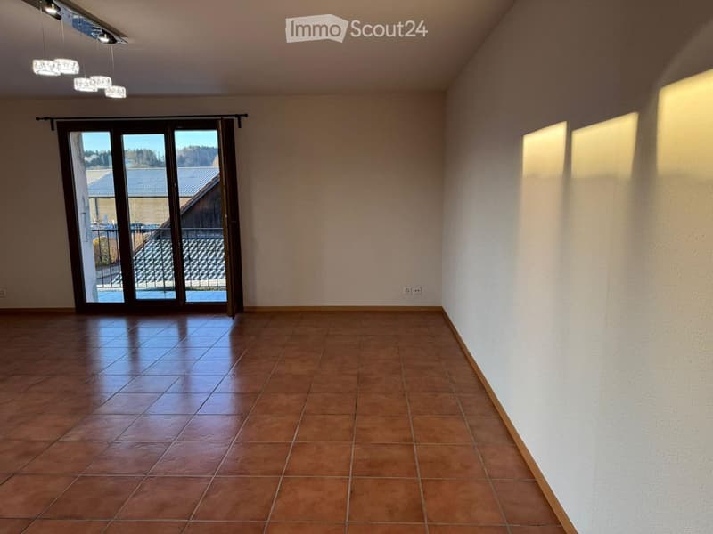 Empty room with tiled floor, large sliding glass door leading to outdoor area, and modern lighting fixture on the ceiling.