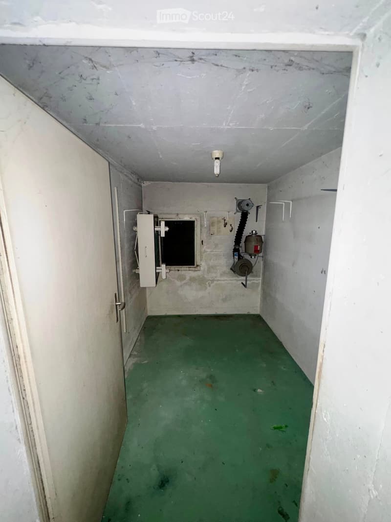 Empty room with green floor, white walls, and a small window. No furniture or equipment present.