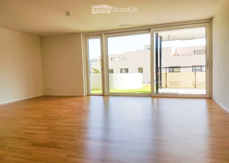 Empty room with wooden flooring and large sliding glass doors leading to a balcony area.