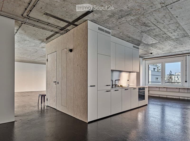Modern kitchen with white cabinets, wooden paneling, stainless steel sink, and a sleek black floor.
