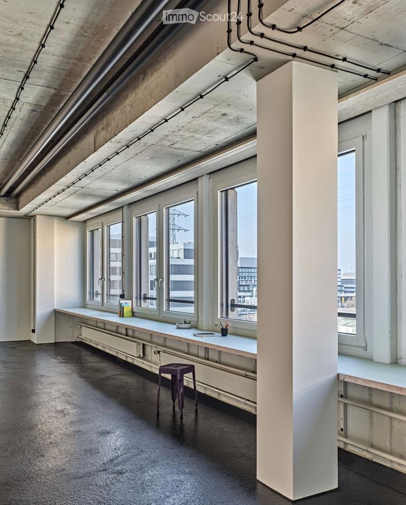 Minimalist room with large windows, exposed concrete ceiling, and a small table with a stool.