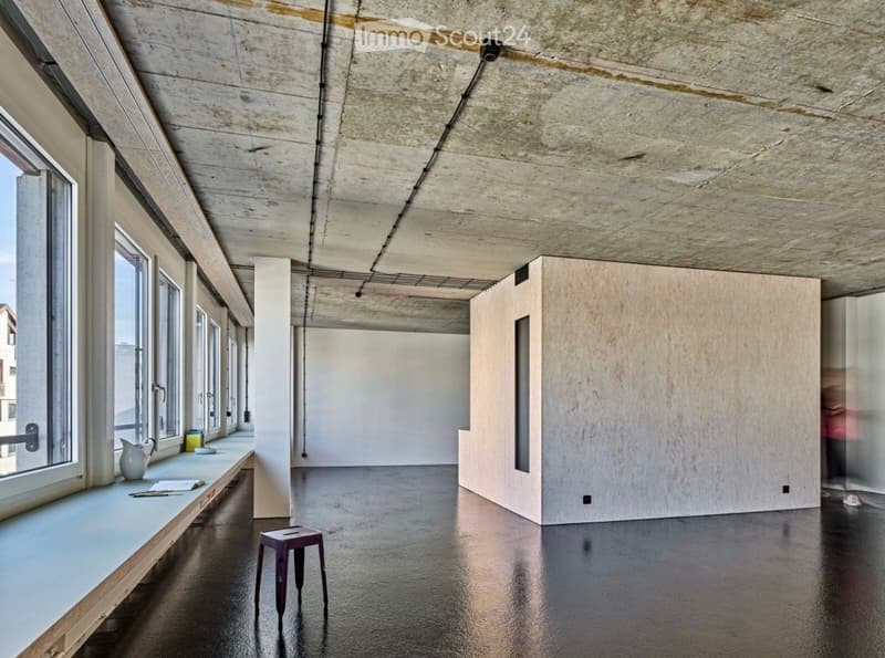 Minimalist room with large windows, polished concrete floor, exposed concrete ceiling, and a small wooden stool near the window.