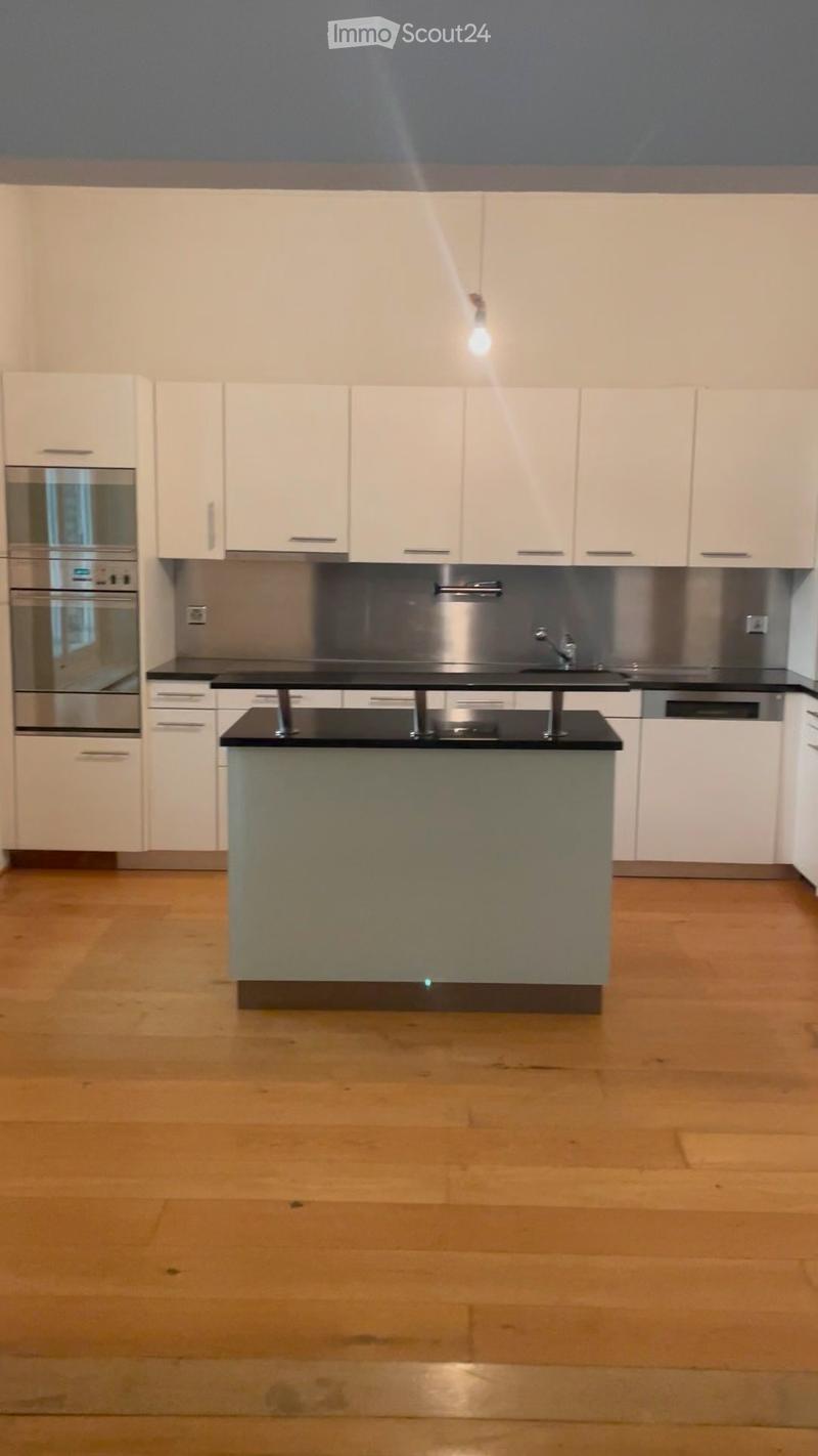 Modern kitchen with white cabinets, stainless steel appliances, and a central island with a black countertop.