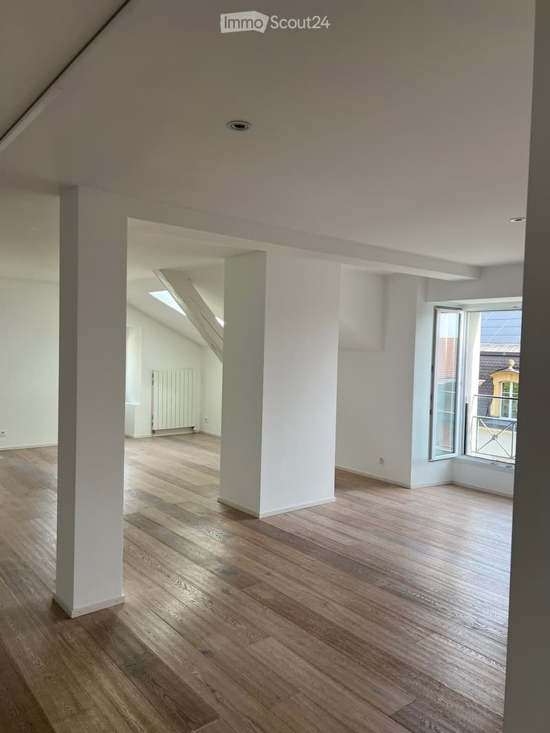 Empty room with wooden flooring, white walls, and a large window with a balcony view.