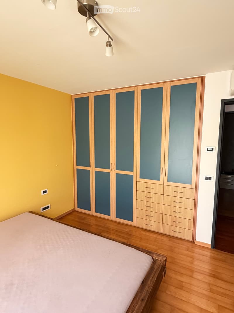 Bedroom with wooden floor, large wardrobe with mirrored doors, and a bed with a light pink duvet.
