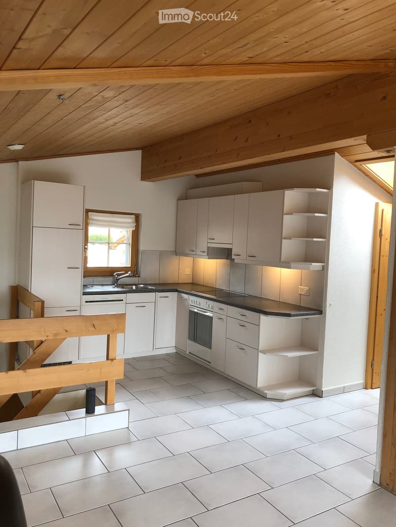Modern kitchen with white cabinets, stainless steel appliances, and a black countertop. Features a window, tiled floor, and built-in shelving.