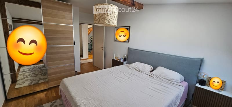 Modern bedroom with a large bed, nightstand, mirror, wardrobe, and decorative lamp.