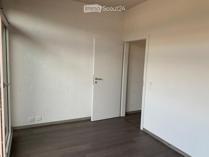 Empty room with wooden flooring, white walls, and a closed white door leading to another space.
