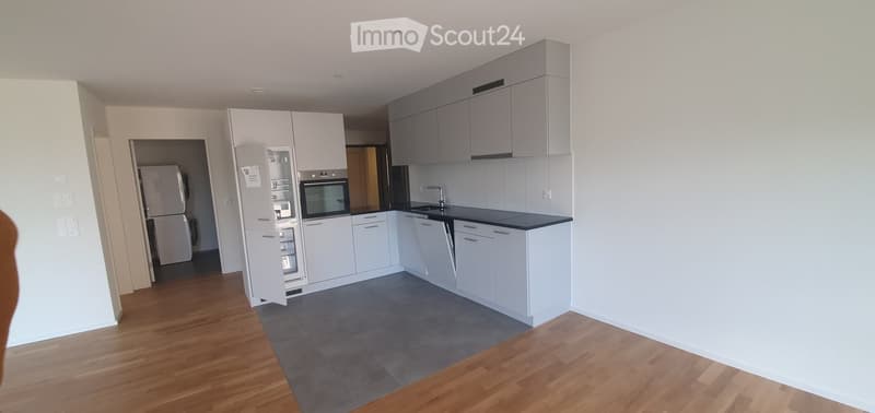 Modern kitchen with white cabinets, stainless steel appliances, and a black countertop. Features a refrigerator, oven, sink, and faucet.