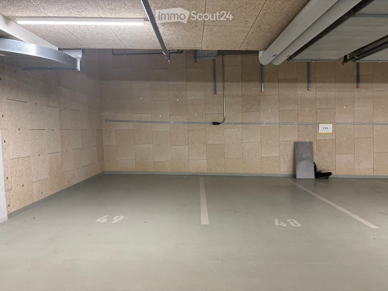 Empty underground parking space with concrete floor, tiled walls, and numbered parking spots48 and 49.