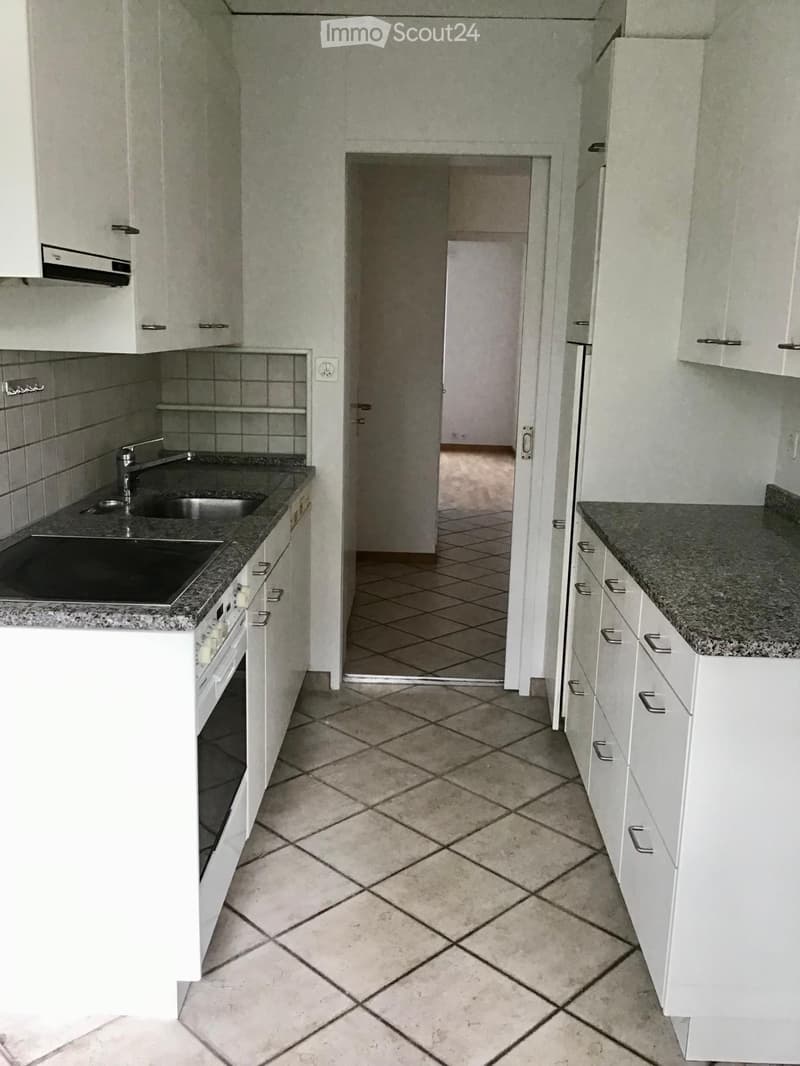 Modern kitchen with white cabinets, granite countertops, and a tiled floor. Features a sink, oven, and built-in cabinets.