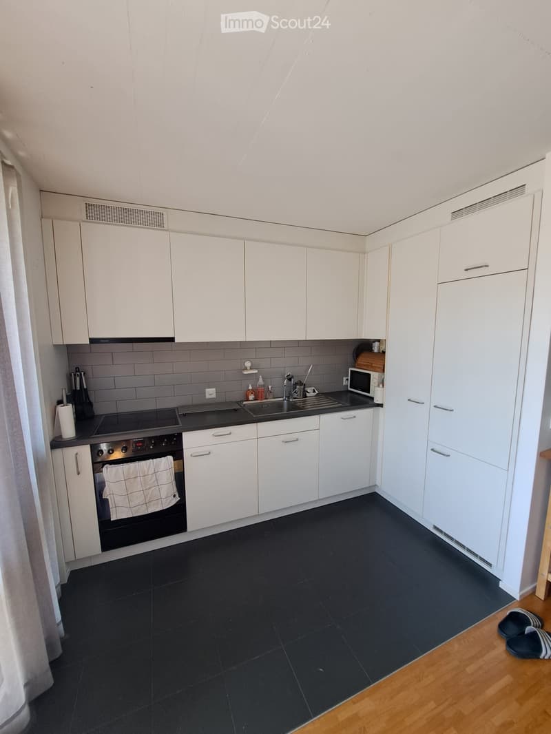 Modern kitchen with white cabinets, black countertops, and stainless steel appliances, including an oven, microwave, and sink.